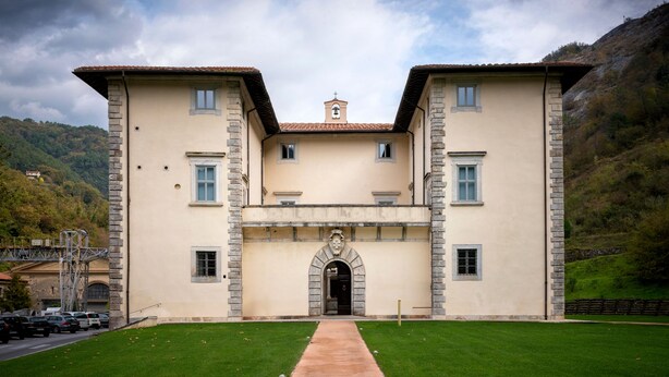 Un edificio grande de dos pisos con una entrada central y un campanario.