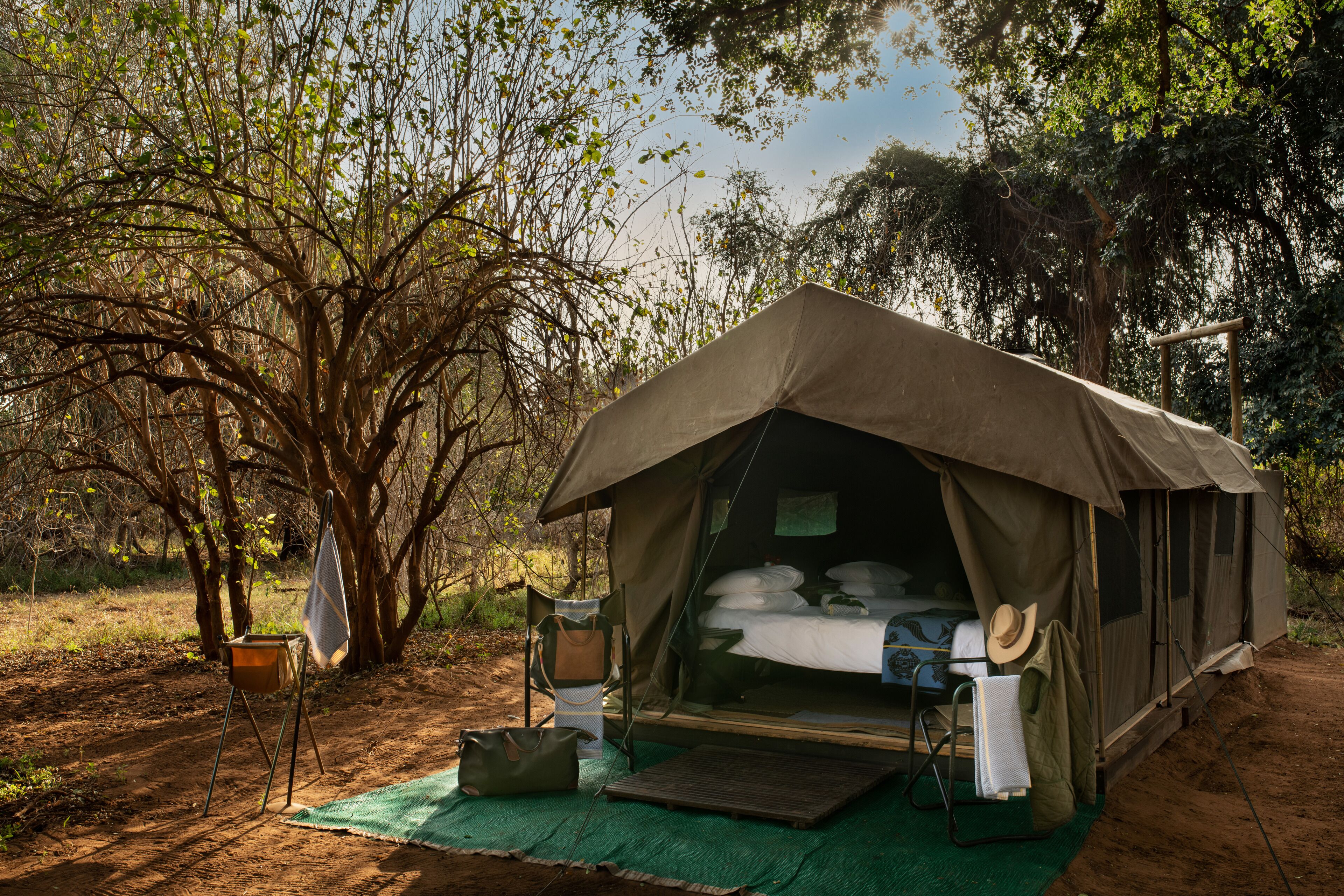 Une tente aménagée avec un lit, une chaise et une table, installée dans un environnement naturel.