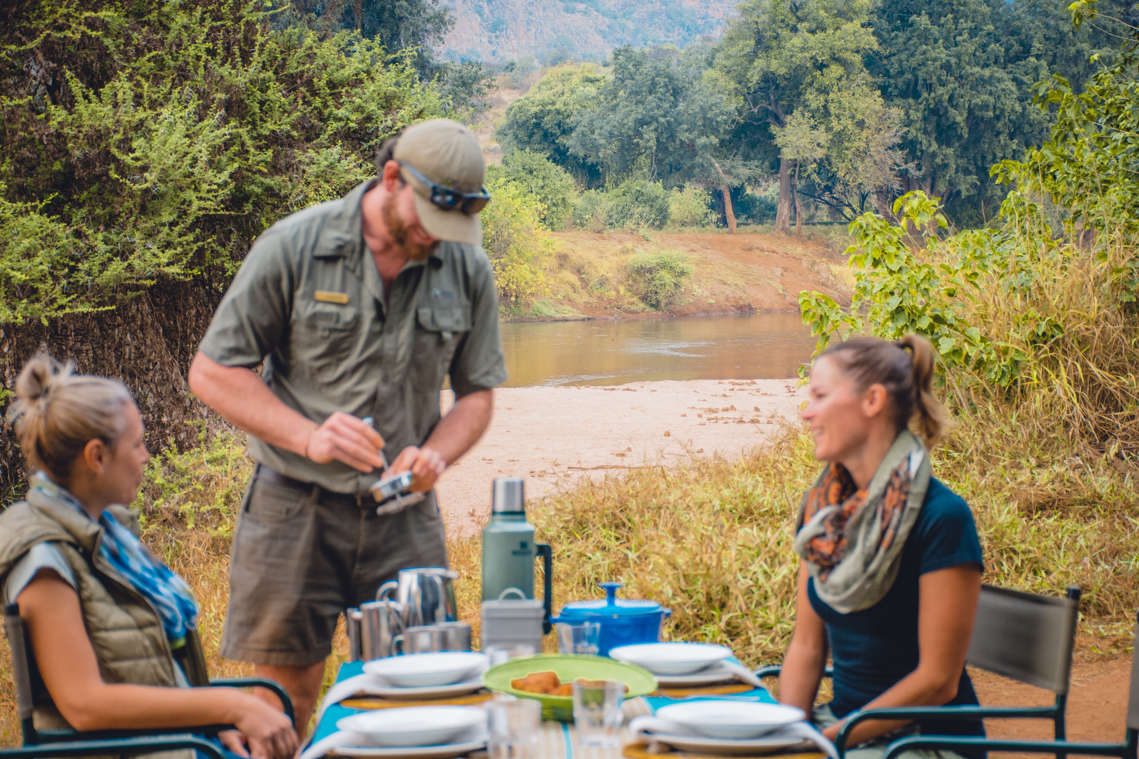 A dining table set outdoors with a river in the background.