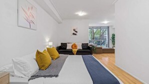 A modern bedroom with a bed, a sofa, and a window.
