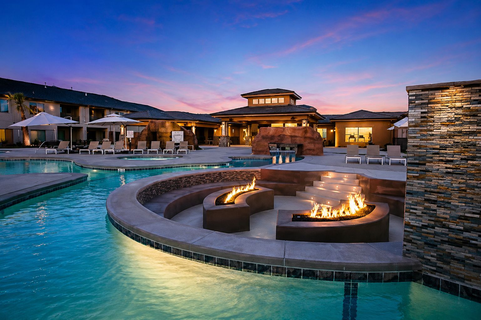A pool area with a fire pit and lounge chairs.