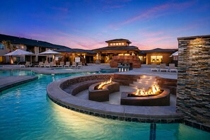 A pool area with a fire pit and lounge chairs.