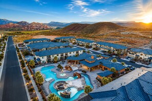 A resort with multiple buildings, a swimming pool, and a mountain backdrop.