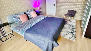 Un dormitorio con cama, una silla, una puerta y un papel tapiz estampado.
