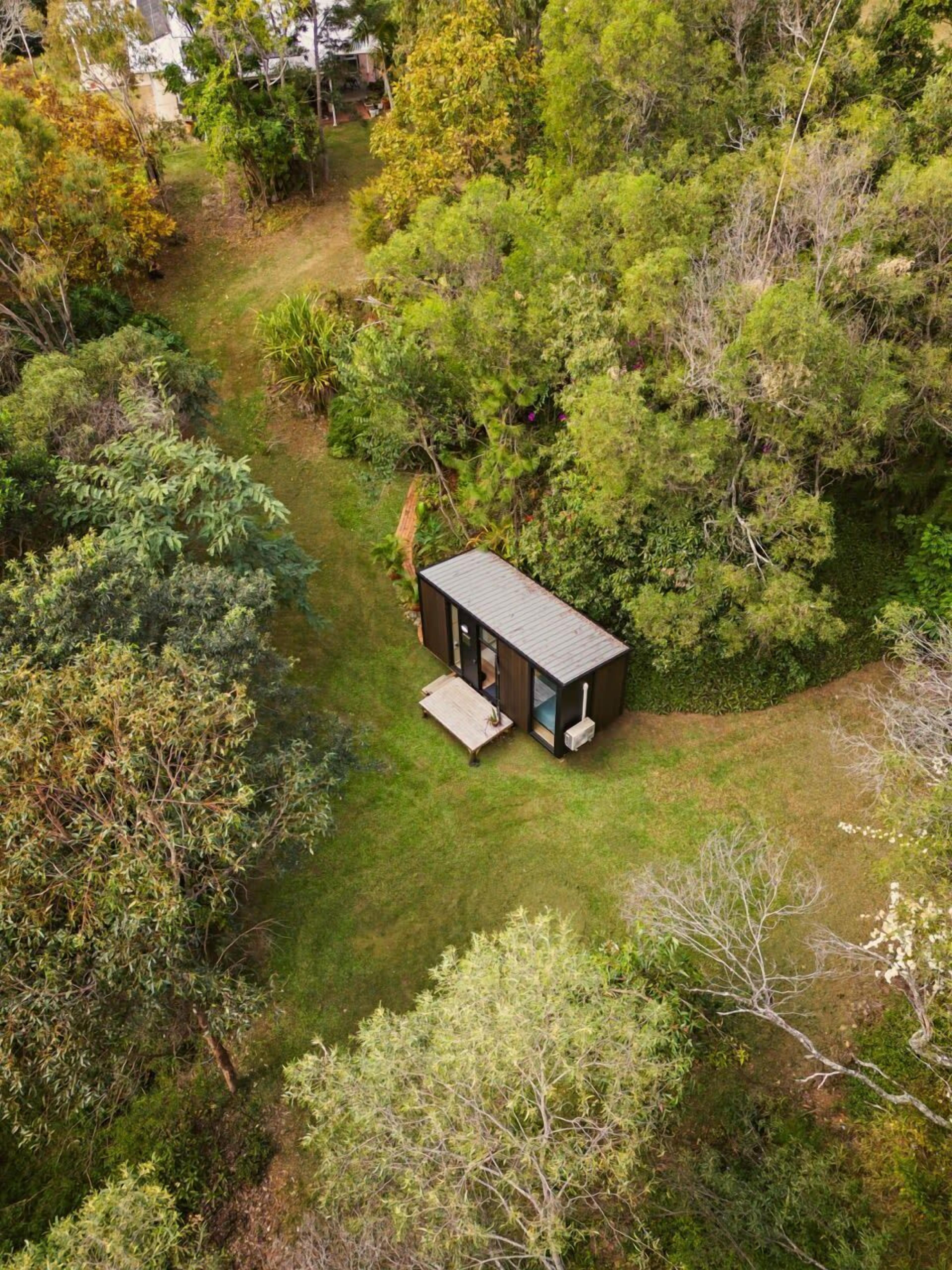 Un piccolo e moderno chalet immerso nel verde, con un sentiero ben definito che conduce all'ingresso.