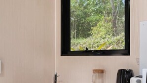 A compact kitchen with a sink, a coffee maker, a toaster, and a dishwasher. - Natural Age by Tiny Away (Bahrs Scrub)