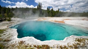 Ein geothermal beheiztes Thermalbad, umgeben von Wald und einem Holzzaun.