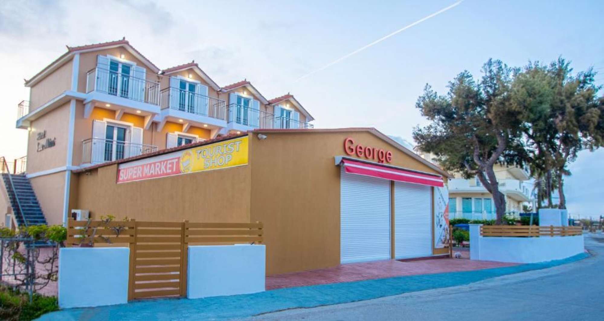 A building with a 'Super Market' and 'Tourist Shop' sign, a 'George' store, and a gated entrance.