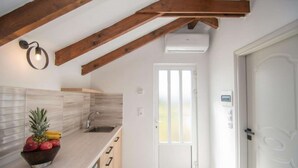 A kitchen with wooden beams, a white door, and a fruit bowl on the counter.