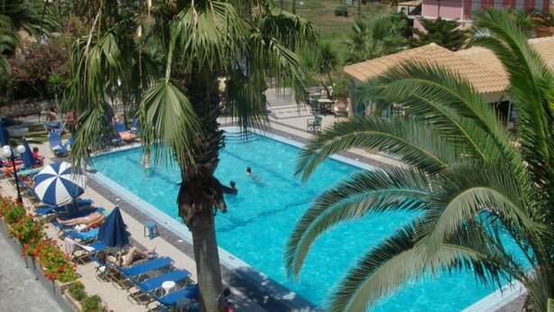 A swimming pool surrounded by palm trees and lounge chairs.