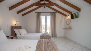 A bedroom with two beds, wooden beams on the ceiling, a TV, a mirror, and a window with curtains.