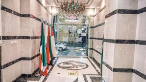 A hallway with marble flooring, a chandelier, and flags on the left. - Al Ghubaishi Plaza (Jeddah)