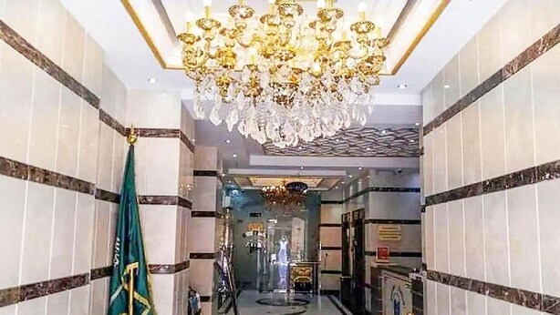 A hallway with a chandelier, marble walls, and a flag. - Al Ghubaishi Plaza (Jeddah)