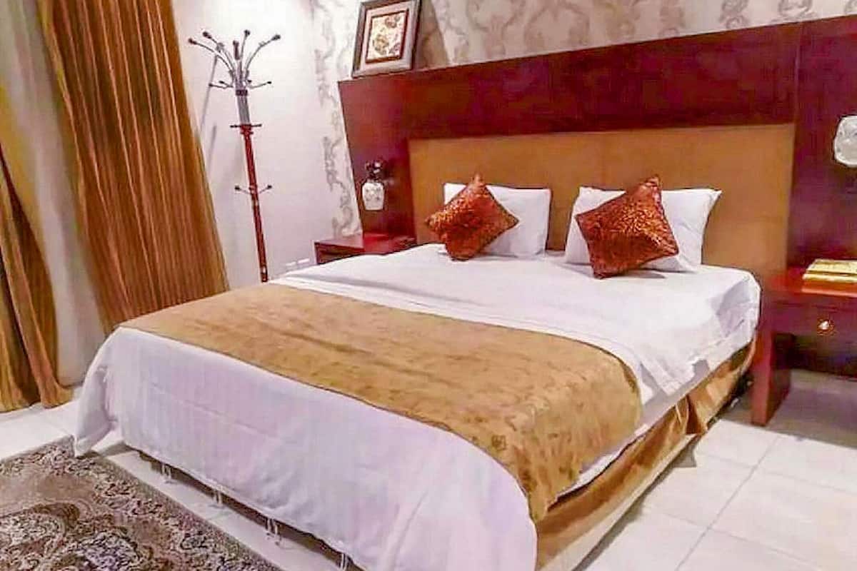 Ein Hotelzimmer mit einem großen Bett, einem Holzkopfende und einem Nachttisch mit einer Lampe.