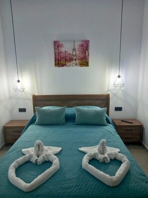Une chambre à coucher avec un grand lit, deux tables de chevet, une tête de lit en bois et un tableau représentant un paysage de parc.