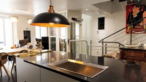 Una cocina moderna con una isla grande, electrodomésticos de acero inoxidable y una lámpara colgante negra.