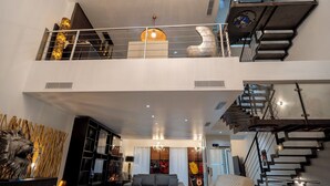 Un interior moderno con una escalera, una sala de estar con sofá y una pared decorativa.