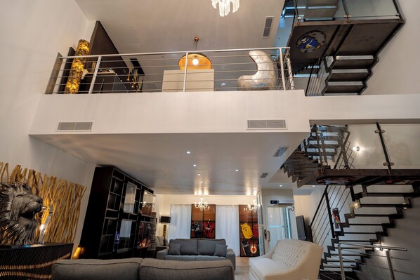A modern interior with a staircase, a living area with a sofa, and a decorative wall. - Venue C - Luxurious & Spacious ~ Sauna ~ Elevator (Cannes)