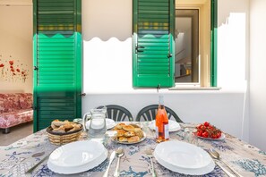 A dining table set with plates, cutlery, a bottle of wine, and a basket of bread. - 3711 Blusea Beach Apt - Piano Terra by Barbarhouse (Manduria)