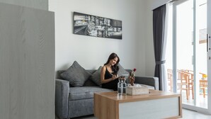 Un salon moderne avec un canapé gris, une table basse en bois et un tableau représentant un paysage urbain accroché au mur.
