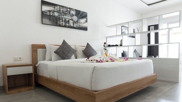 Une chambre moderne avec un cadre de lit en bois, une literie blanche et un tableau représentant un paysage urbain au-dessus du lit.