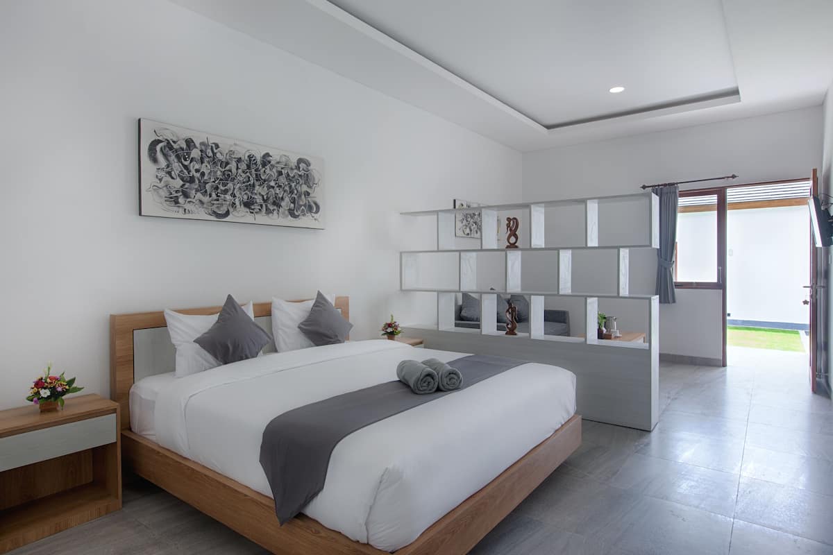 Ein modernes Schlafzimmer mit einem großen Bett, Nachttischen, einem an der Wand befestigten Kunstwerk und einer integrierten Regaleinheit.