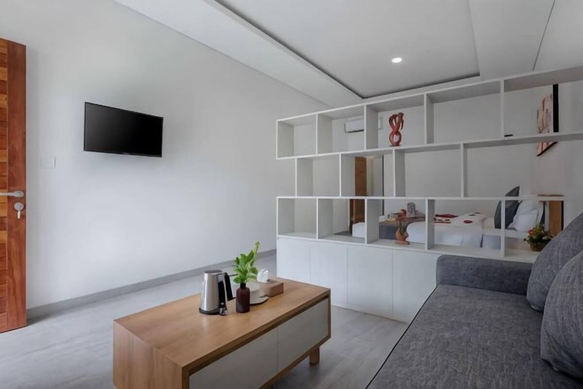 Ein modernes Wohnzimmer mit einem Holztisch, einem grauen Sofa und einem weißen Bücherregal.