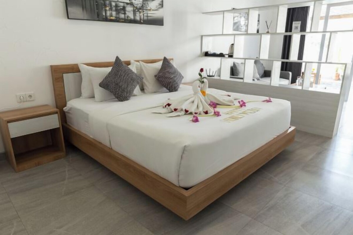 Une chambre d’hôtel moderne avec un cadre de lit en bois, du linge de lit blanc et un décor central en forme de cygne.