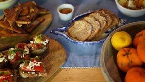 A table with various dishes including bread, a bowl of oranges, and a small dish of sauce. - Superior double room (Neos Marmaras)