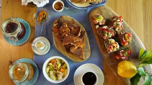 A wooden table with various food items, including bread, a bowl of fruit salad, and a cup of coffee. - Superior double room (Neos Marmaras)