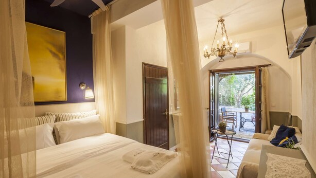 A hotel room with a bed, a chandelier, a balcony with outdoor furniture, and a painting on the wall. - Superior double room (Neos Marmaras)