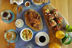 Ein Holztisch mit verschiedenen Speisen, darunter Brot, eine Obstsalatschale und eine Kaffeetasse.