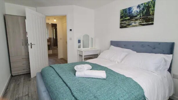 Une chambre à coucher avec un lit, un bureau et un tableau accroché au mur.