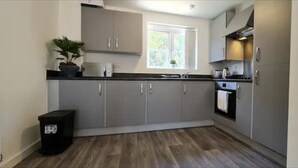 Une cuisine moderne avec des meubles gris, un plan de travail noir et une fenêtre qui laisse entrer la lumière naturelle.