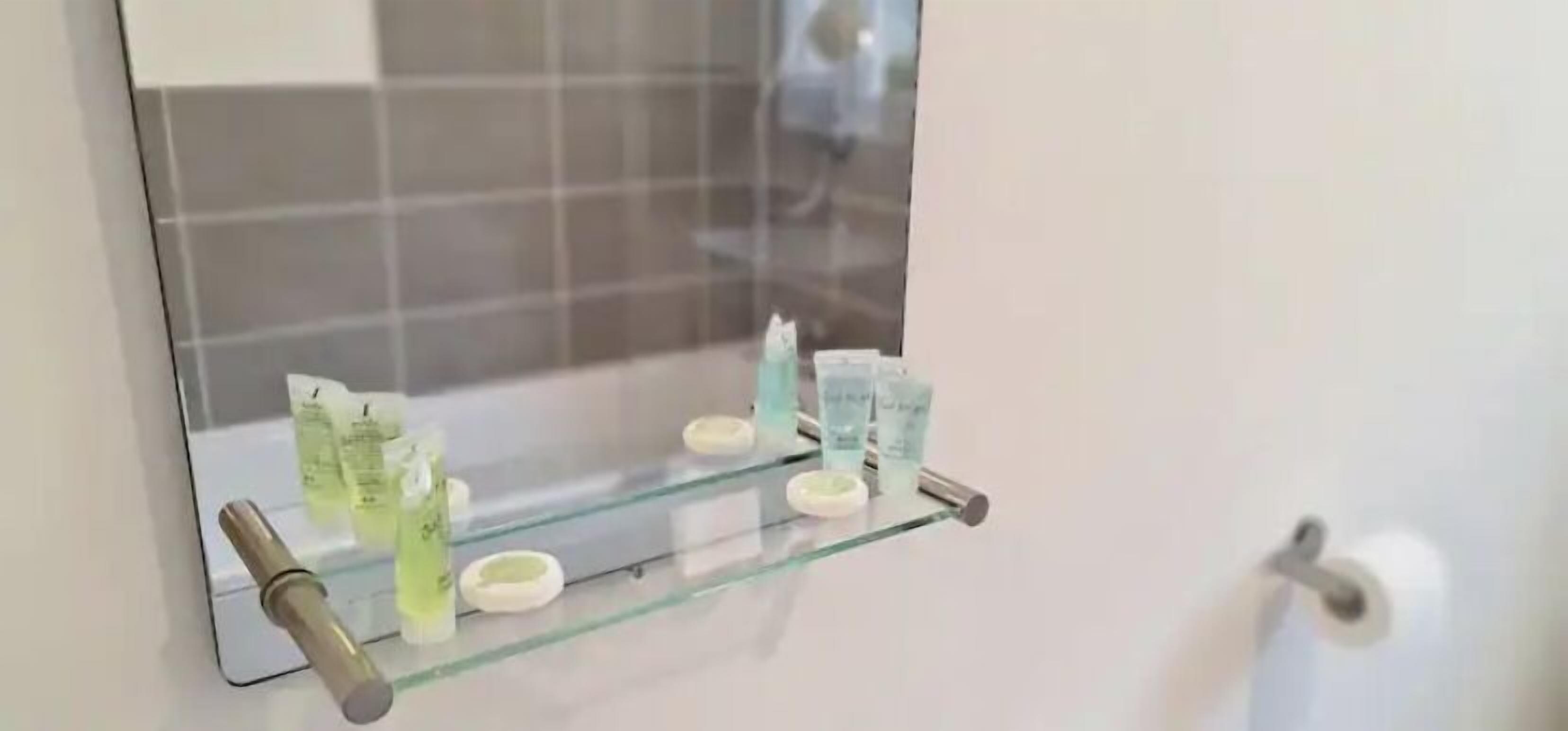 A bathroom with a glass shelf holding toiletries.