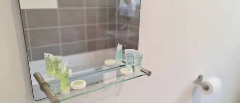 A bathroom with a glass shelf holding toiletries.