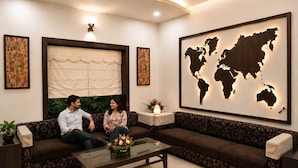 A modern living room with a sofa, a coffee table, and a world map mural. - Hotel Cresent Near Assi Ghat (Varanasi)