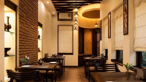 A restaurant with brick walls, wooden tables, and chairs, featuring a warm ambiance. - Hotel Cresent Near Assi Ghat (Varanasi)