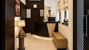 A hotel reception area with a desk, a clock, and a sign listing amenities like a restaurant and rooftop. - Hotel Cresent Near Assi Ghat (Varanasi)