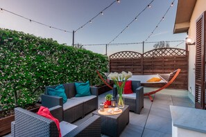 An outdoor patio with wicker furniture, a hammock, and string lights. - Casa Tofanelli in Lucca (Lucca)