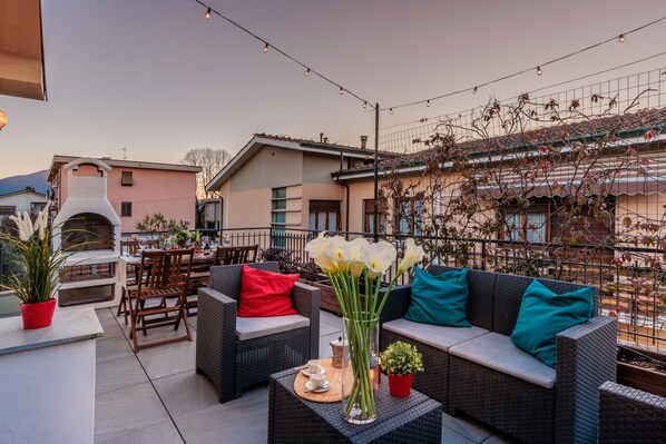 An outdoor patio area with wicker furniture, a pizza oven, and string lights. - Casa Tofanelli in Lucca (Lucca)