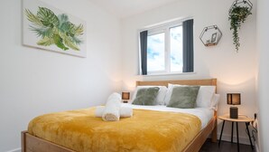 A neatly made bed with a yellow blanket, a wooden headboard, and two bedside lamps.