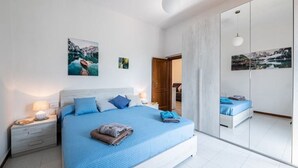 A modern bedroom with a large bed, bedside tables, and artwork on the walls.