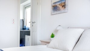 Um quarto com uma cama, uma mesa de cabeceira, uma luminária, uma pequena planta e um quadro na parede.