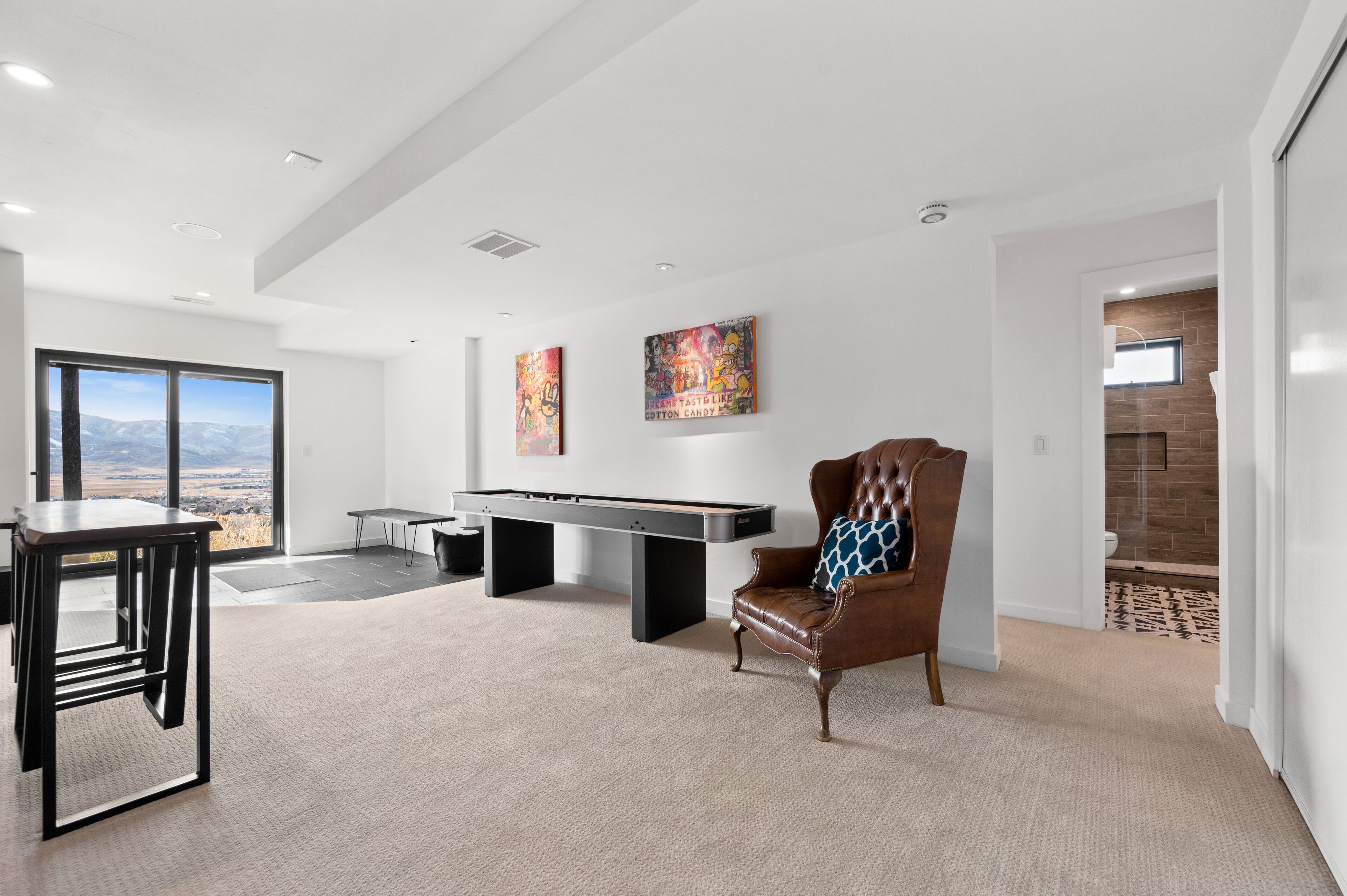 A modern living room with a pool table, a leather armchair, and artwork on the walls.