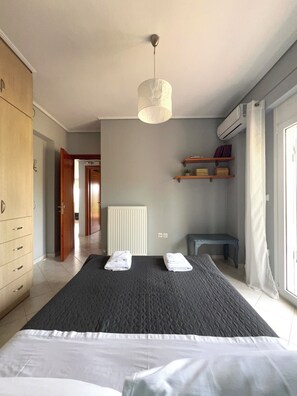 Een slaapkamer met een bed, nachtkastje, kledingkast, radiator en een plank met boeken.