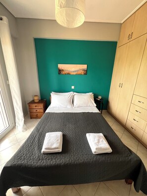 A bedroom with a bed, a nightstand, a wardrobe, and a painting on the wall.