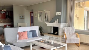 Een woonkamer met een bank, salontafel, open haard en plafondventilator.