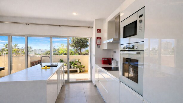 Una cocina moderna con una isla grande, horno empotrado y vistas al exterior.