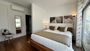 Un dormitorio con una cama grande, una lámpara de noche, una silla y un ventanal con cortinas.
